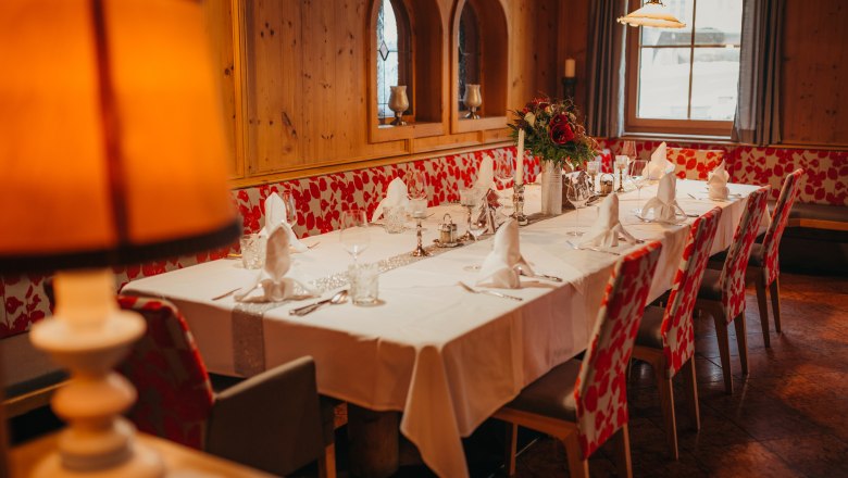 Elegantes Gastzimmer mit gedecktem Tisch, Holzverkleidung und Blumenarrangement.