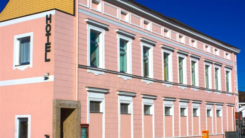 Ein rosa Geb&auml;ude mit der Aufschrift 'Hotel' an der Fassade.