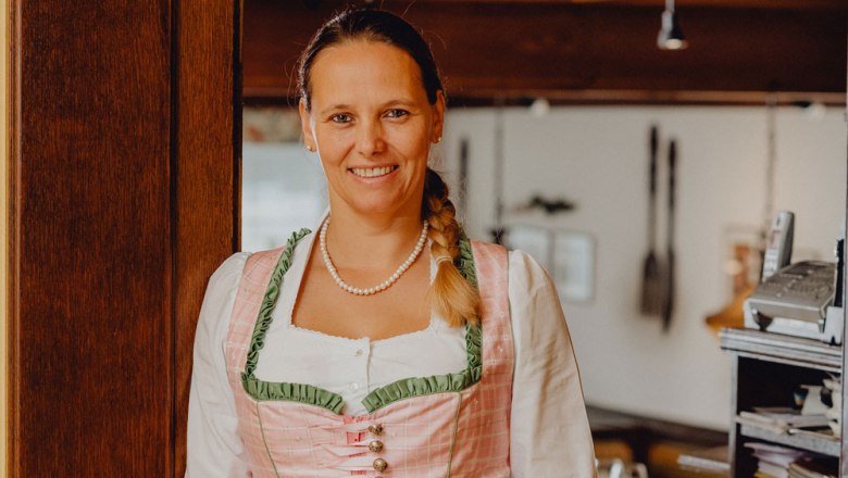 Frau in traditioneller Tracht l&auml;chelt in einem Restaurant.