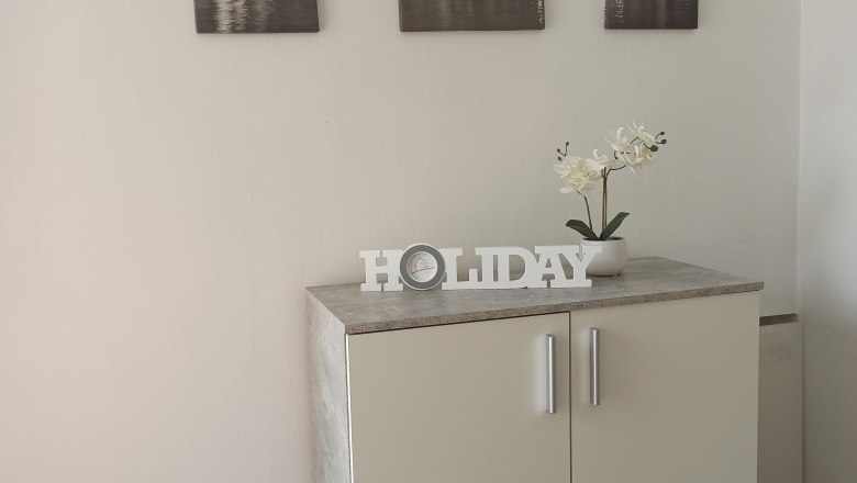 Ein wei&szlig;er Schrank mit Dekoration und drei Stadtbildern an der Wand.