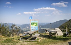 Picknicktische und Wanderschild mit Bergblick bei der Edelwei&szlig;h&uuml;tte am Schneeberg.