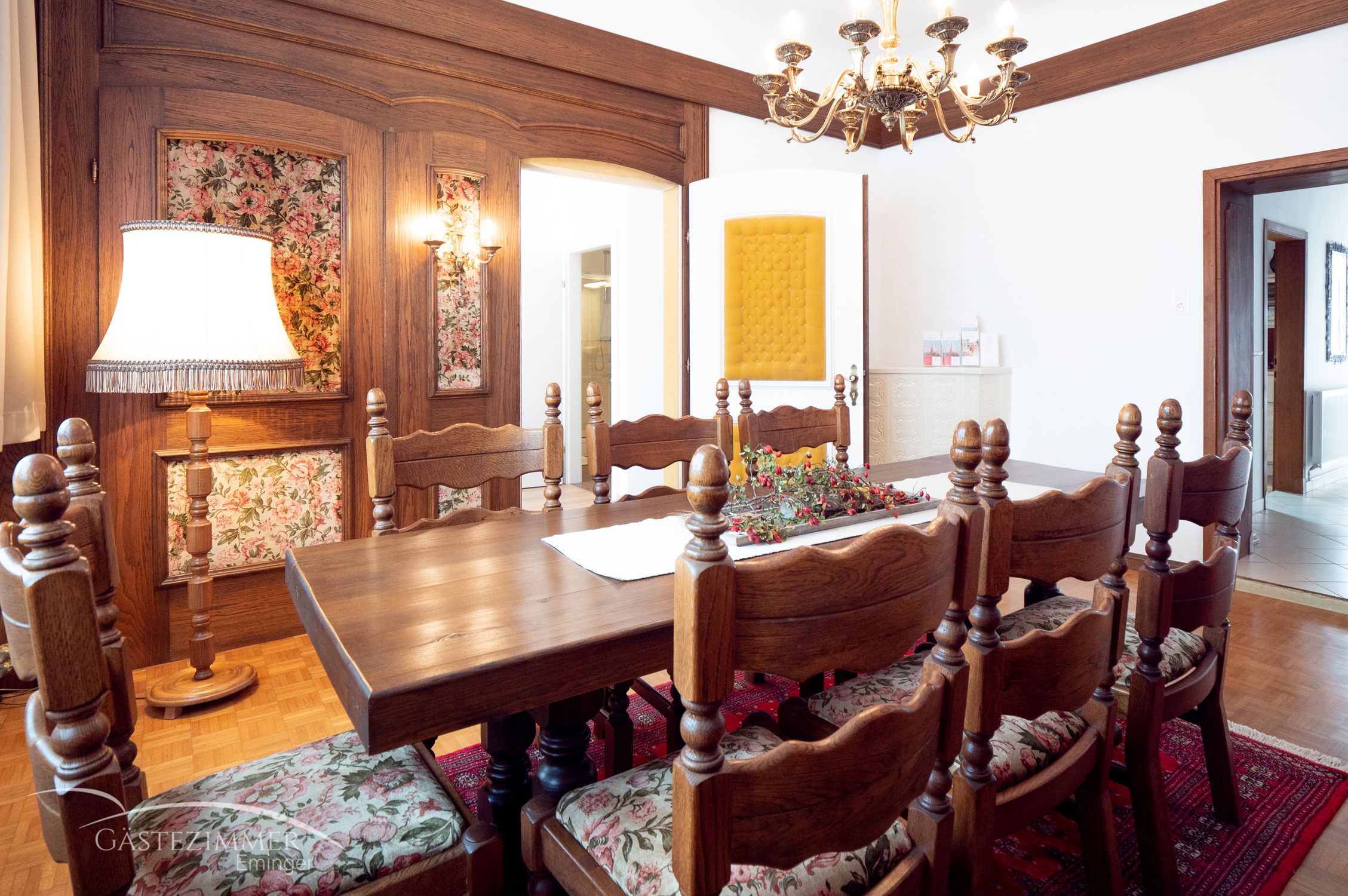 Rustikales Esszimmer mit Holzmöbeln, Kronleuchter und floralen Mustern.