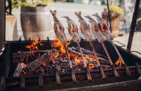 Steckerlfisch über offenem Feuer gegrillt, traditionelle Zubereitung.