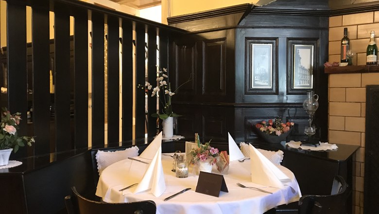 Ein gemütlicher Tisch in einem traditionellen Restaurant mit dunkler Holzvertäfelung und dekorativen Blumen.