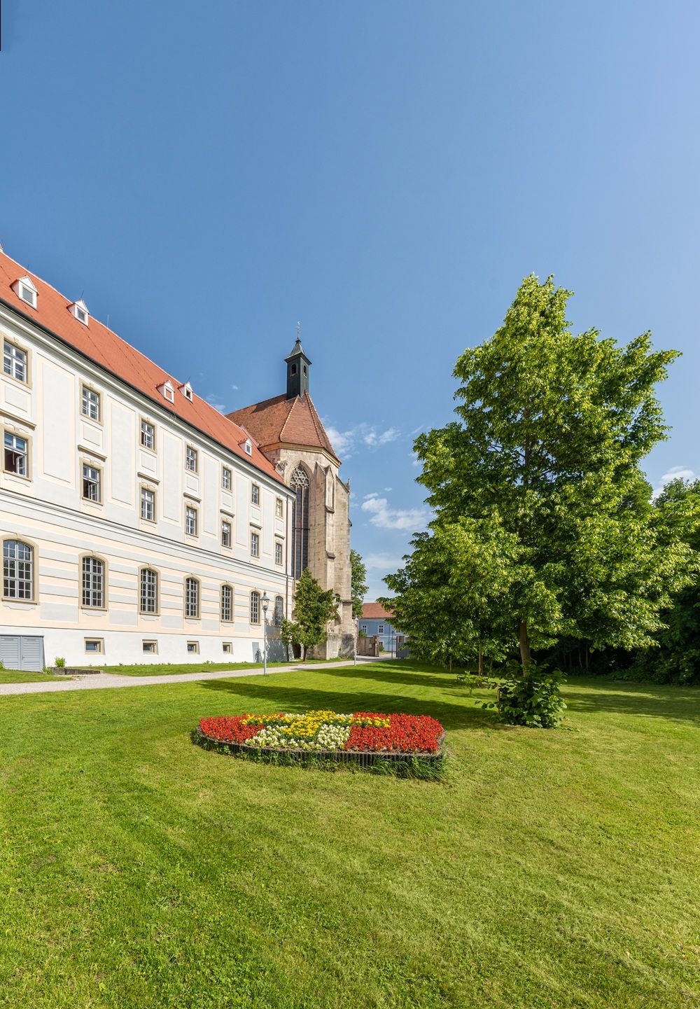 Stift Neukloster mit Garten und Blumenbeet im Vordergrund.