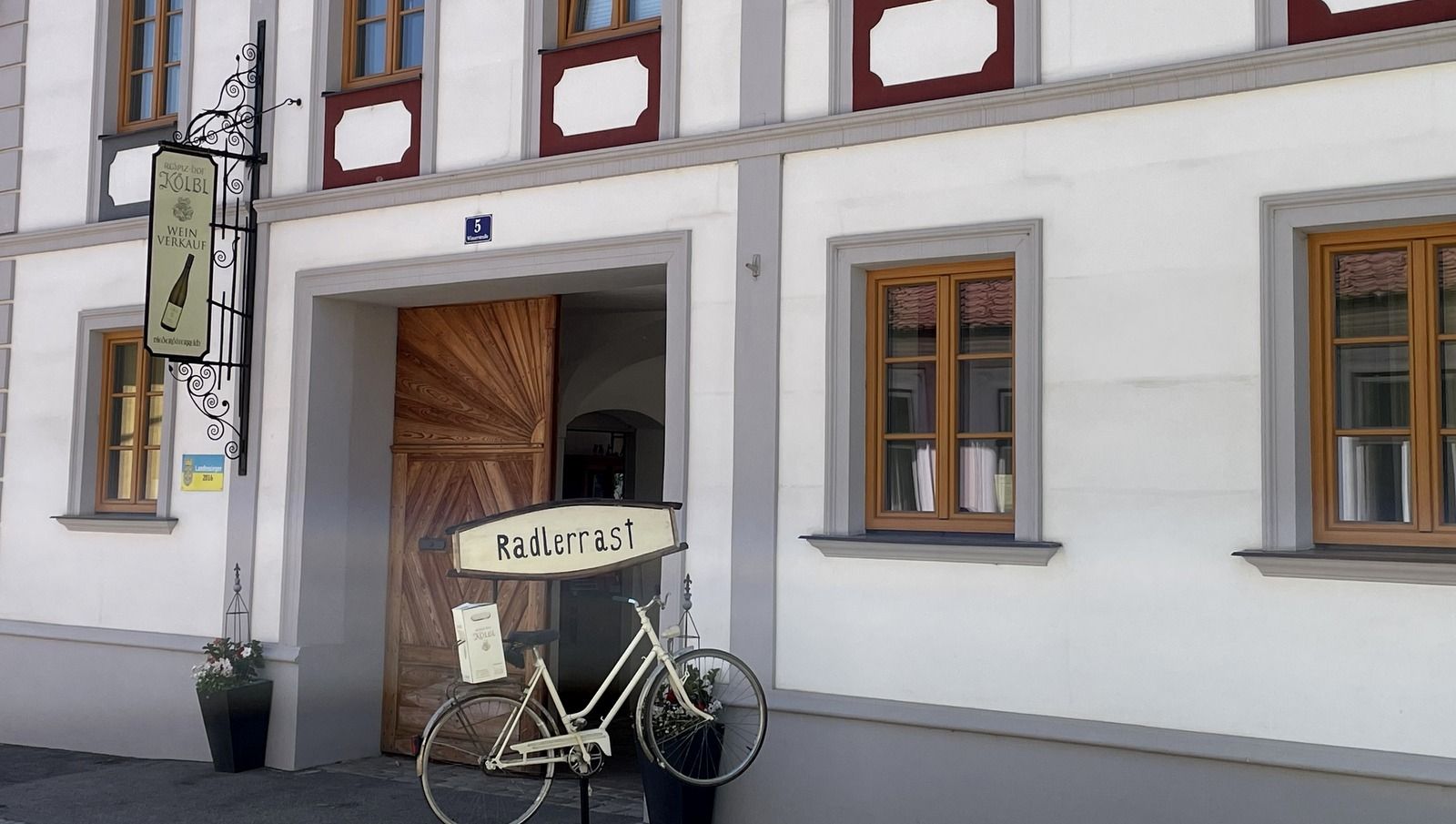 Fassade eines Gebäudes mit Schild 'Radlerrast' und einem dekorativen Fahrrad.