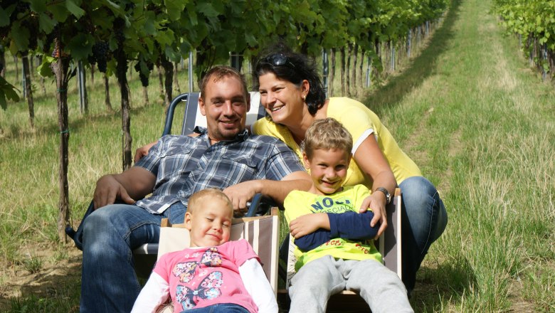 Familie sitzt auf Liegest&uuml;hlen in einem Weinberg.