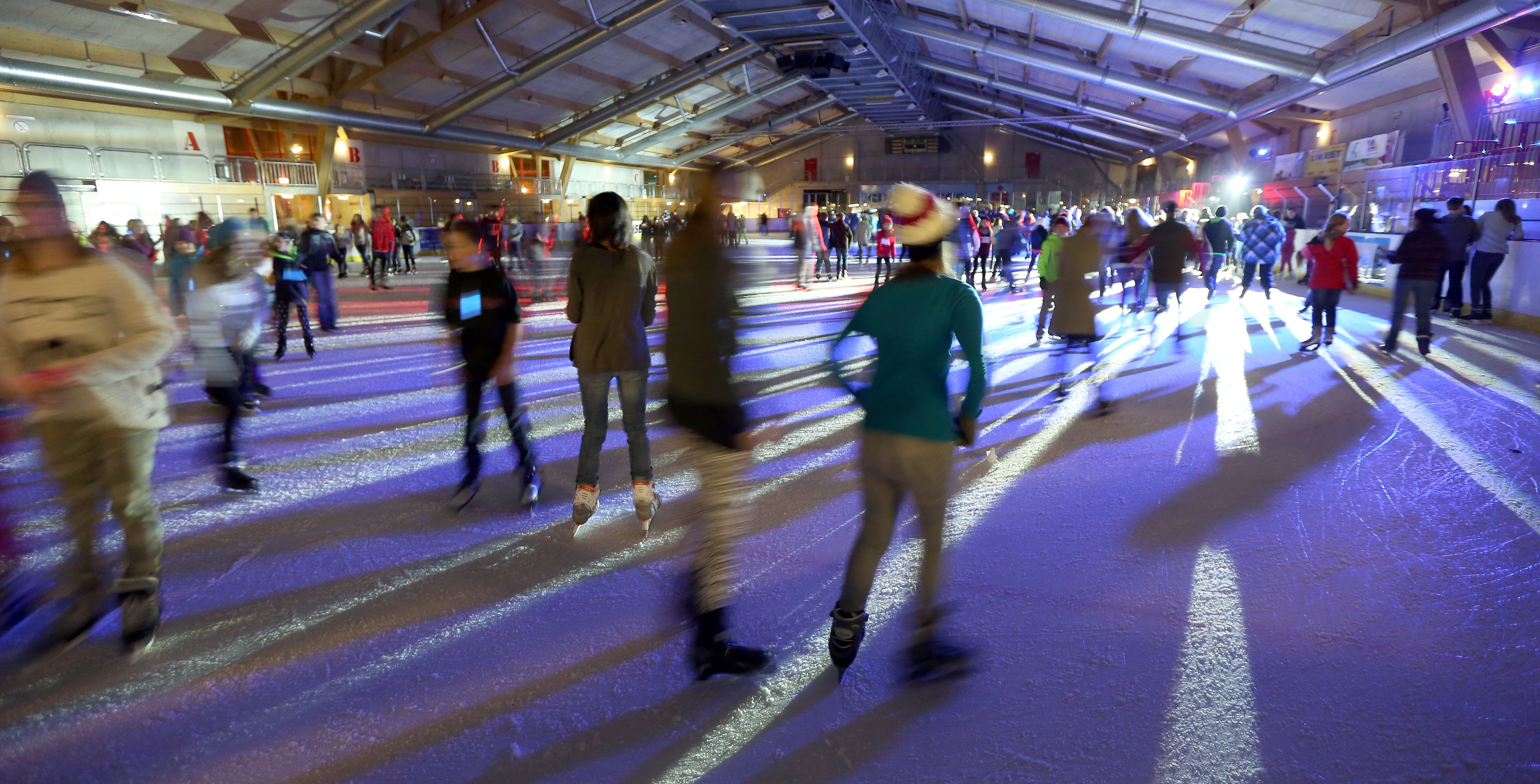 Menschen beim Eislaufen in einer beleuchteten Eishalle.