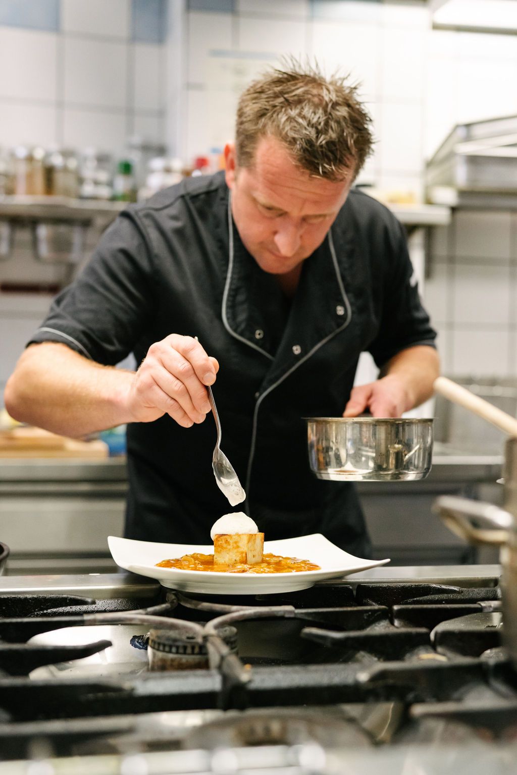Ein Koch verziert ein Gericht in einer professionellen Küche.