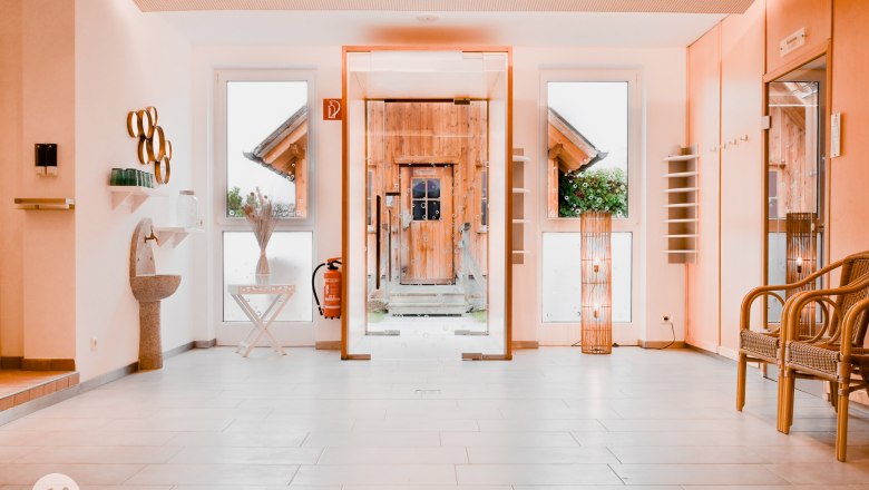 Moderner Aufenthaltsbereich mit Glaswand, Holztür, Dekorationen und Sitzgelegenheiten.