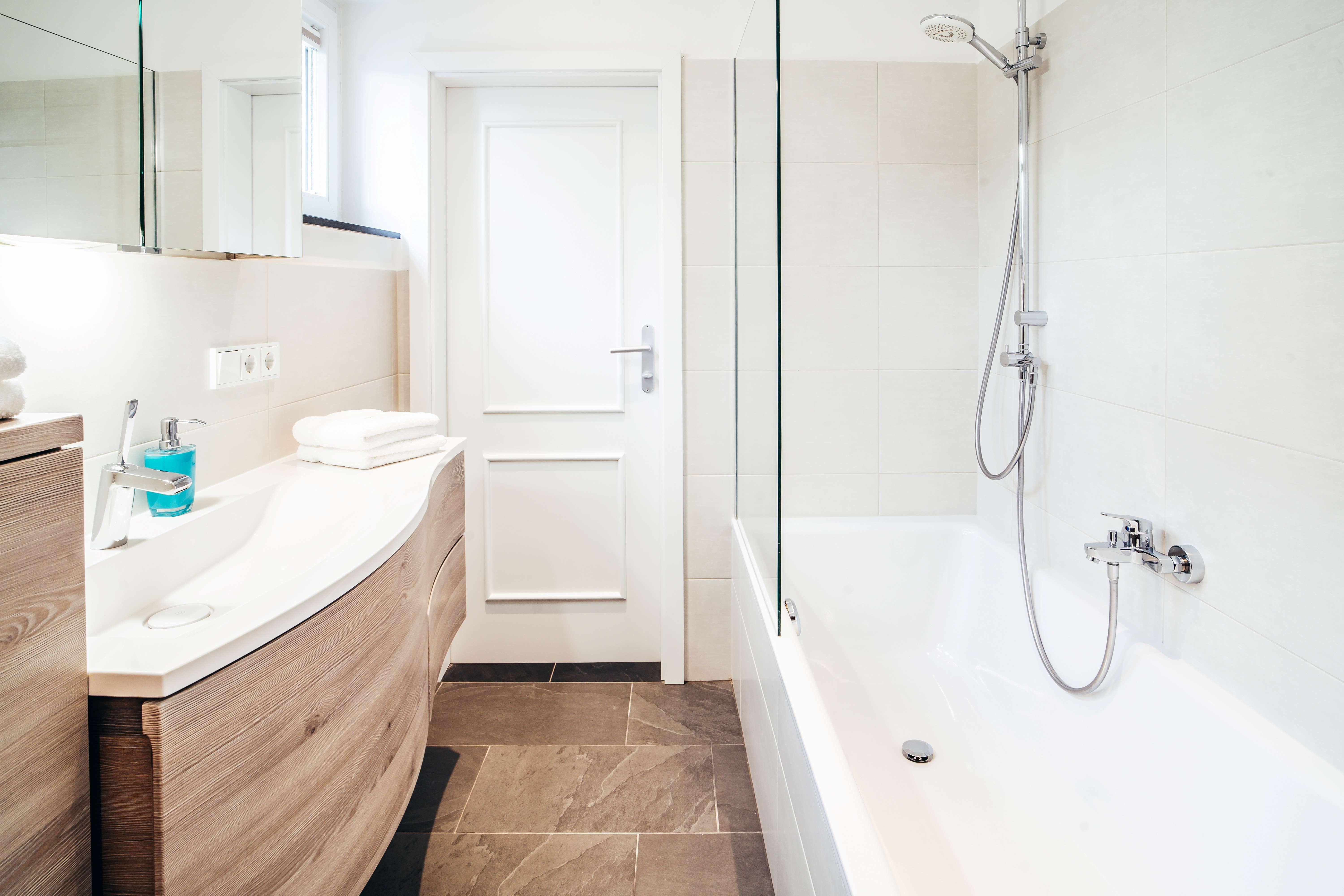 Modernes Badezimmer mit Badewanne, Waschbecken und Spiegel.