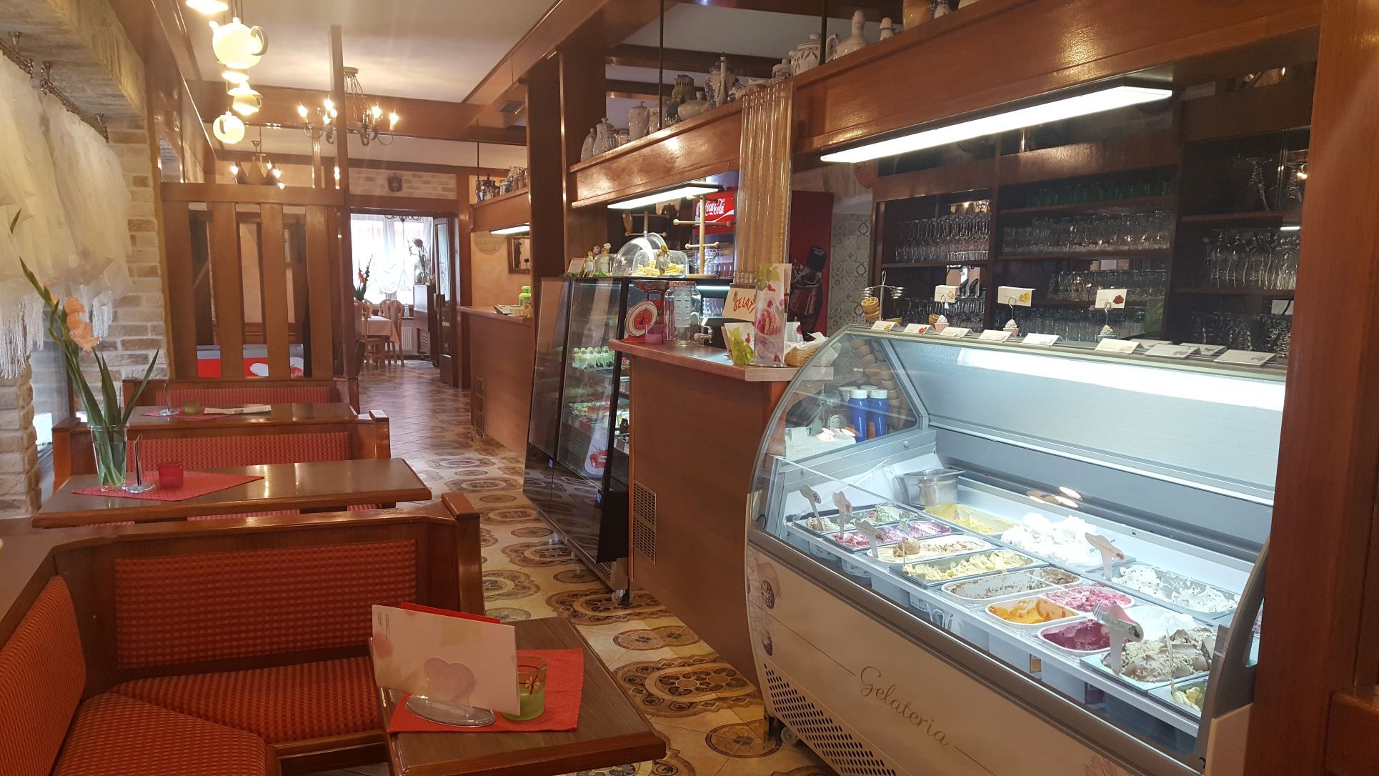 Innenansicht eines Cafés mit Eistheke und Sitzbereichen.