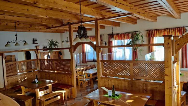 Innenansicht eines rustikalen Heurigenlokals mit Holzm&ouml;beln und Pflanzen.