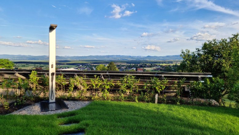 Solar-Dusche im Garten mit Blick auf Landschaft und blauen Himmel.
