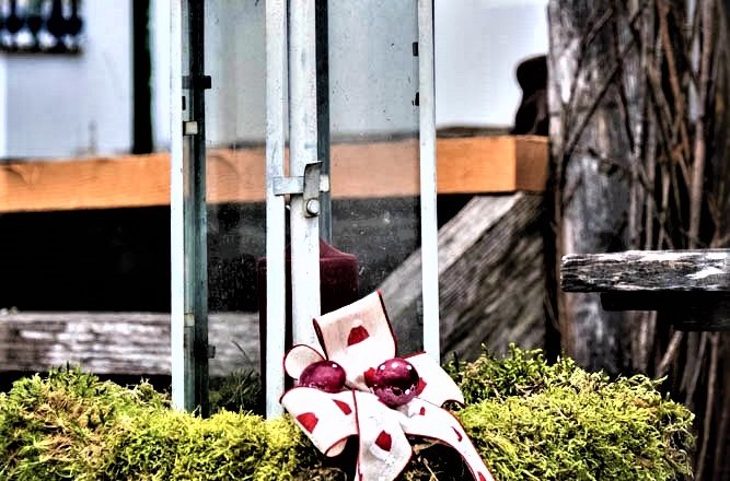 Laterne mit Moos und Schleife dekoriert.