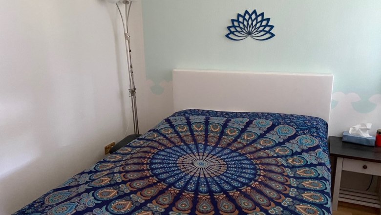 Schlafzimmer mit Wasserbett, bunter Bettdecke und Lotus-Wanddekoration.