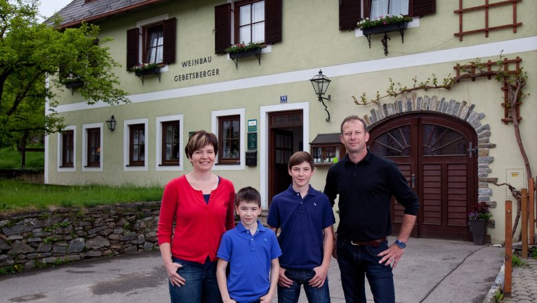 Eine Familie steht vor einem Geb&auml;ude mit der Aufschrift 'Weinbau Gebetsberger'.