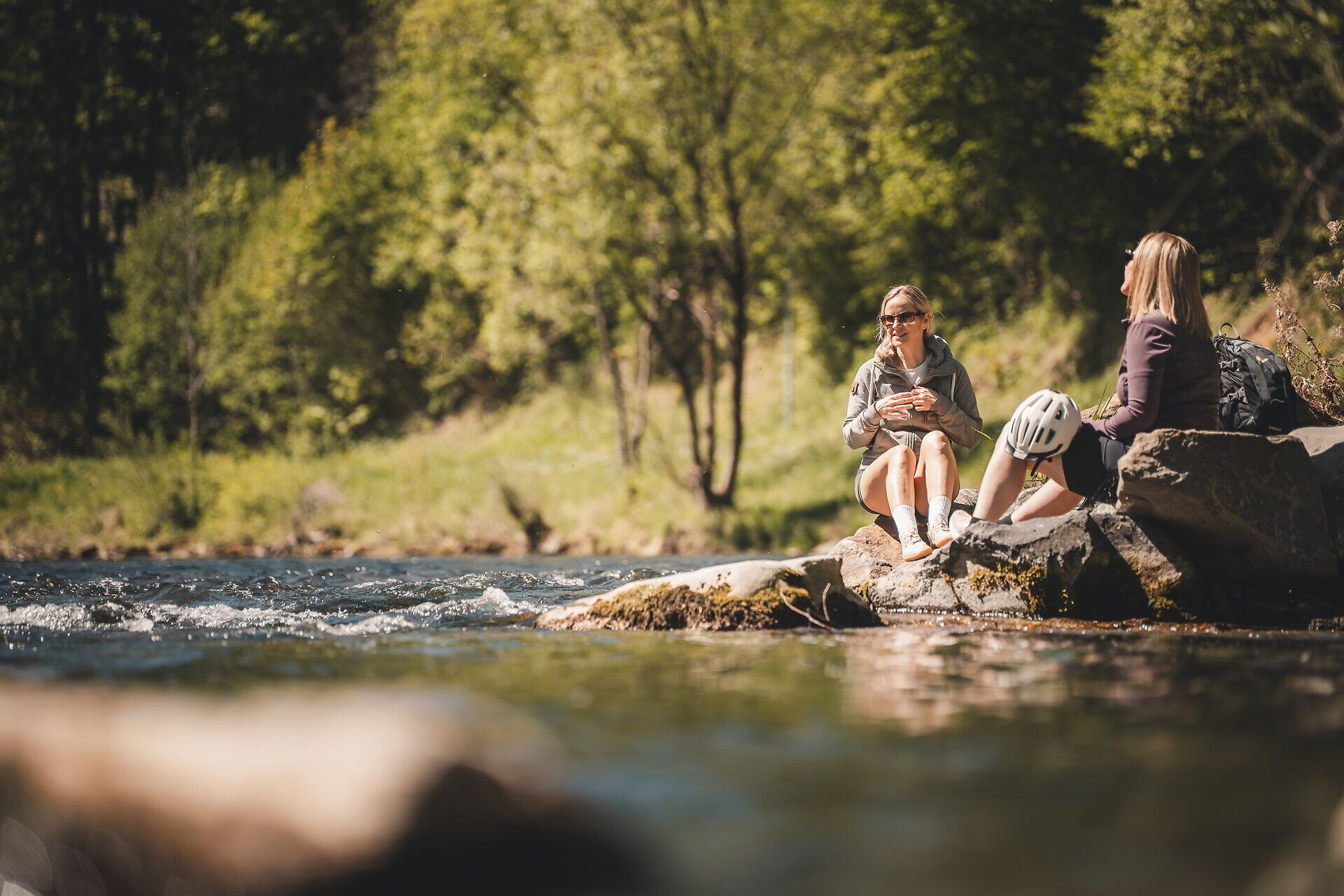 Zwei Radfahrerinnen genießen eine kurze Pause am Wasser.