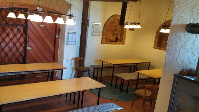 Innenansicht eines Heurigen mit Holztischen, B&auml;nken und rustikaler Dekoration.