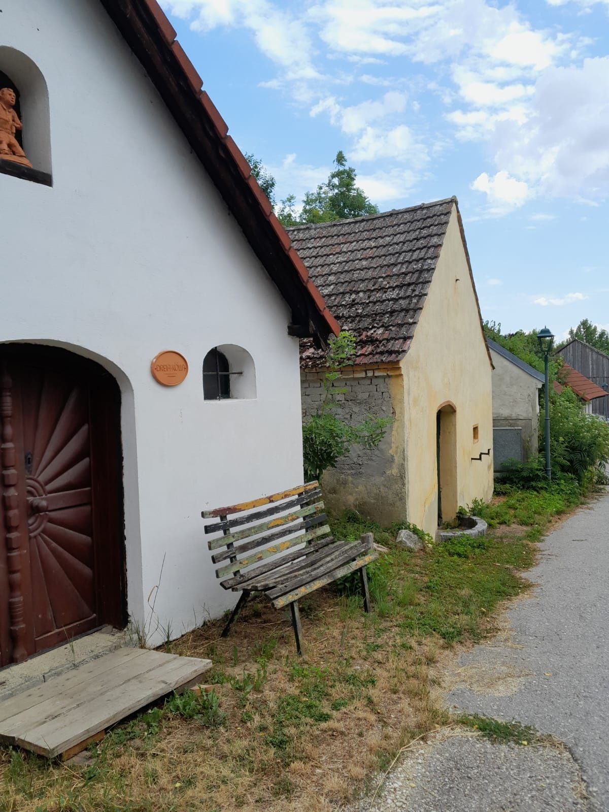 Eine Reihe von kleinen, traditionellen Gebäuden mit Ziegeldächern und einer Holzbank davor.