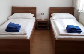 Zwei Einzelbetten in einem Zimmer mit Wanddekoration und blauen Handt&uuml;chern.