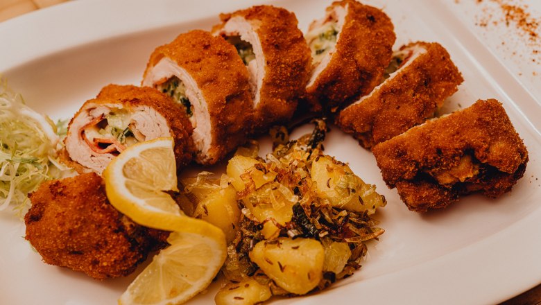 Gefülltes gebackenes Putenfilet mit Kartoffelbeilage und Zitronenscheiben auf einem weißen Teller.