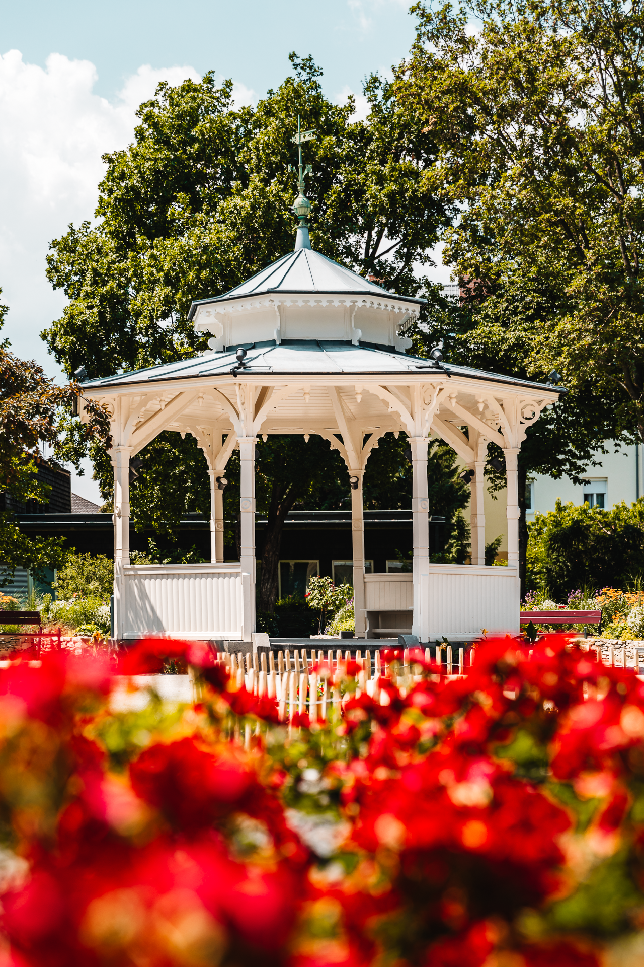Weißer Pavillon vor blühenden roten Blumen