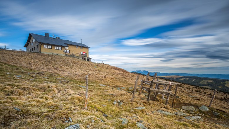 Das Wetterkoglerhaus am Hochwechsel, © Wiener Alpen, Christian Kremsl Das Wetterkoglerhaus auf einem Hügel mit bewölktem Himmel im Hintergrund.