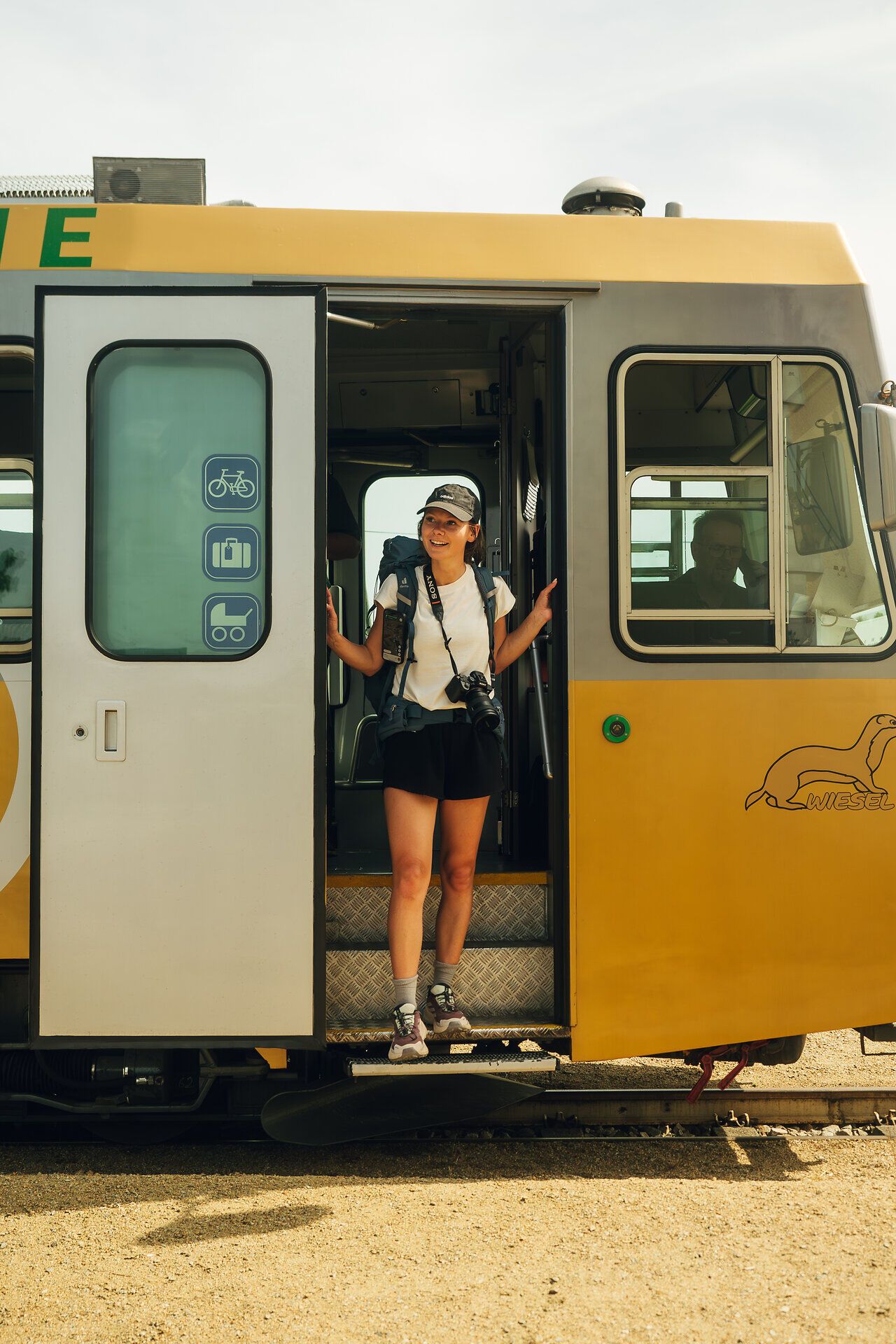 Frau steigt gerade aus dem goldenen Triebwagen der Waldviertelbahn lächelnd aus