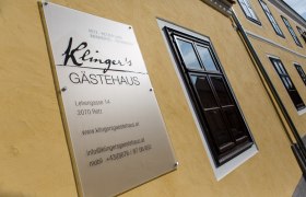 Schild von Klinger's G&auml;stehaus an einer gelben Hauswand.
