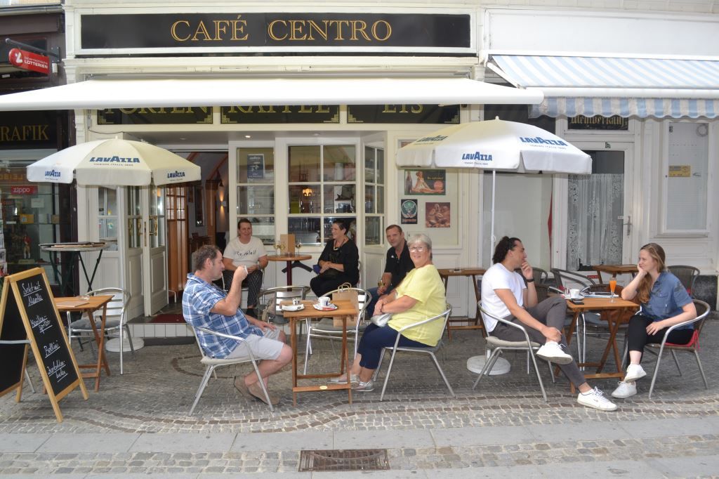 Menschen sitzen vor einem Café mit dem Namen Café Centro.