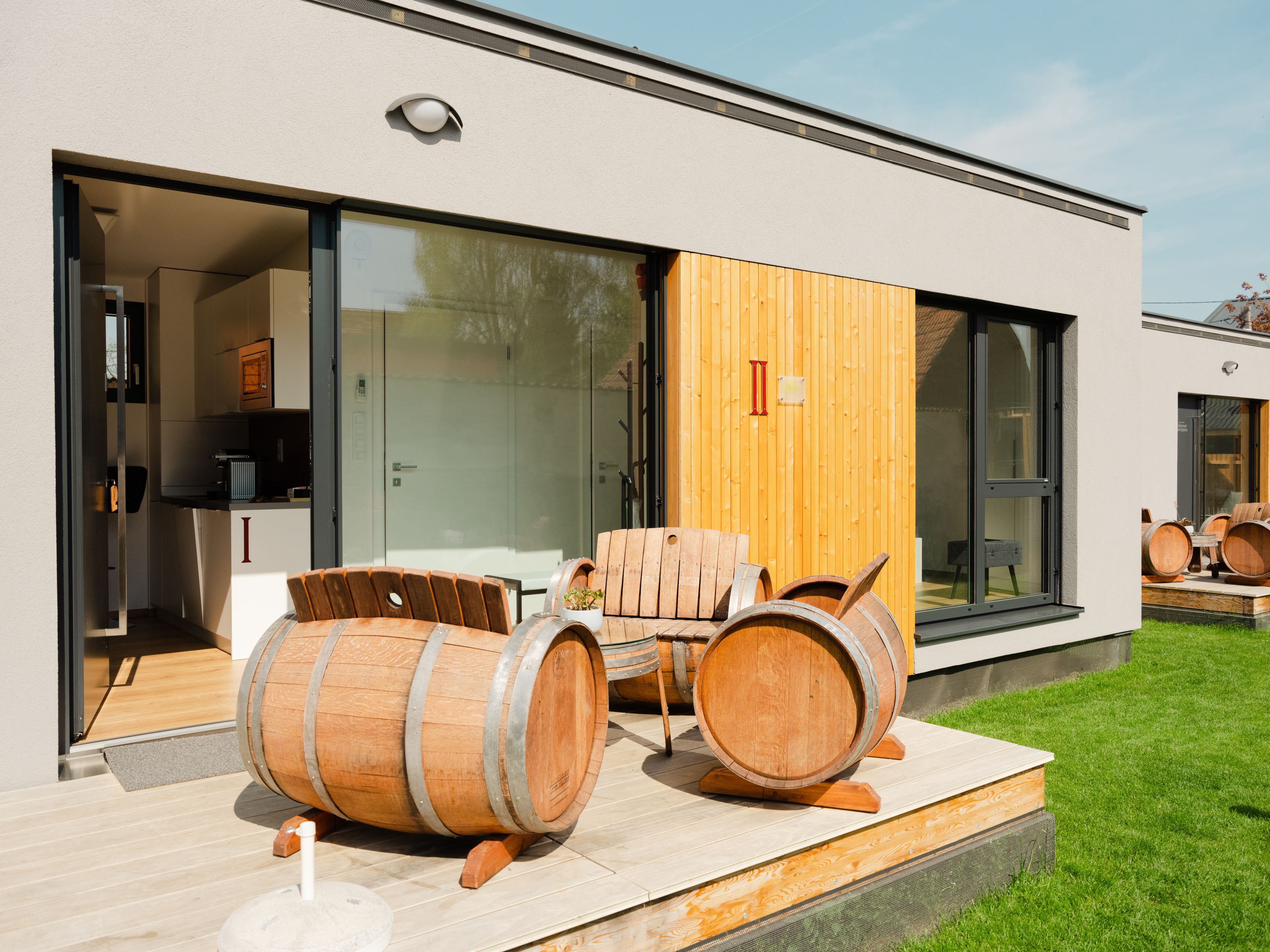 Moderne Terrasse mit Weinfassmöbeln vor einem Appartement.
