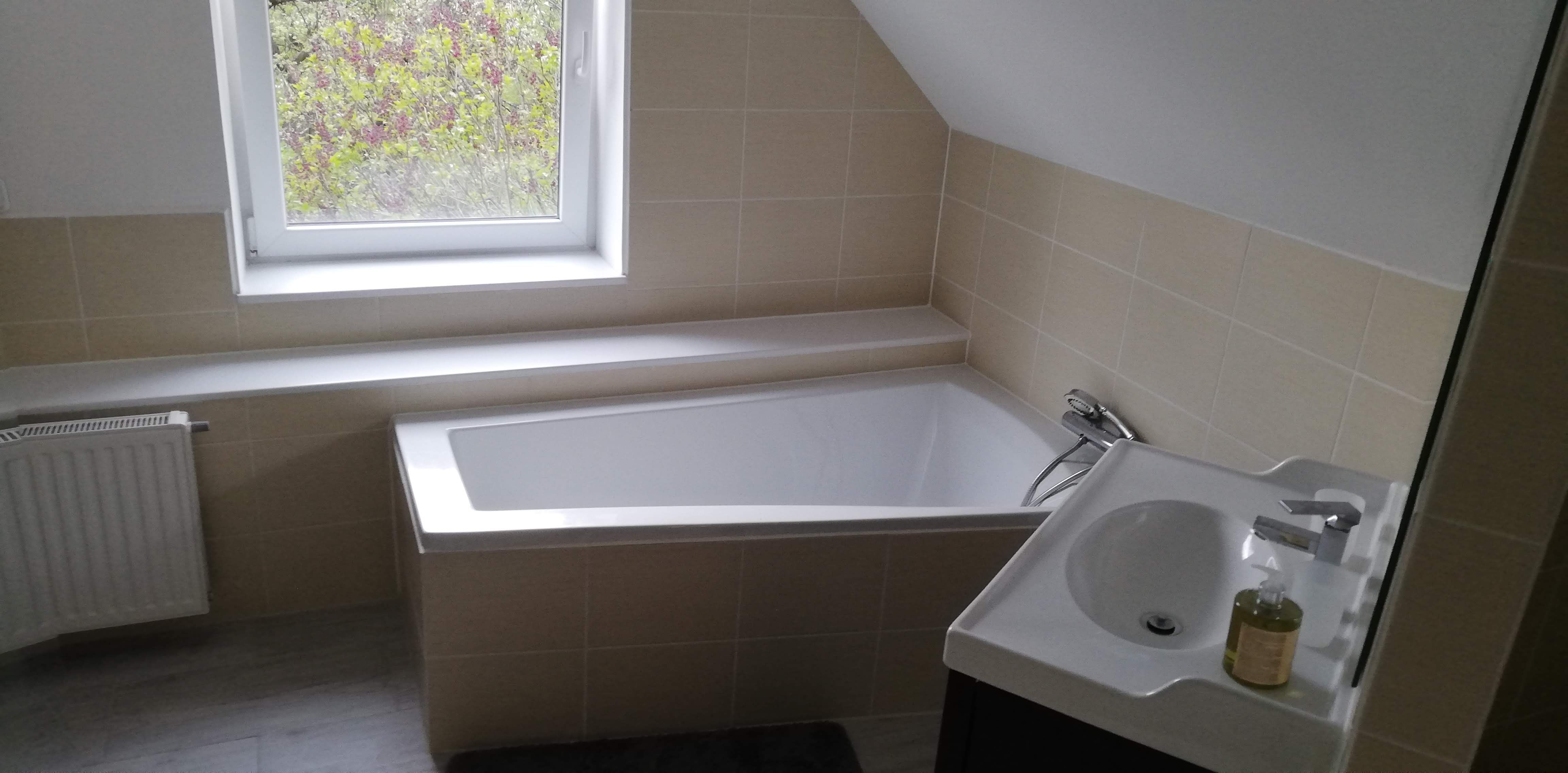 Modernes Badezimmer mit Badewanne, Waschbecken und Fenster.
