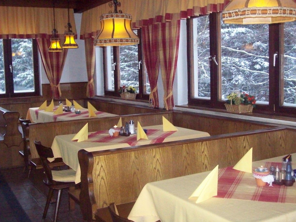 Innenansicht eines gemütlichen Gasthauses mit Holzmöbeln und gedeckten Tischen.