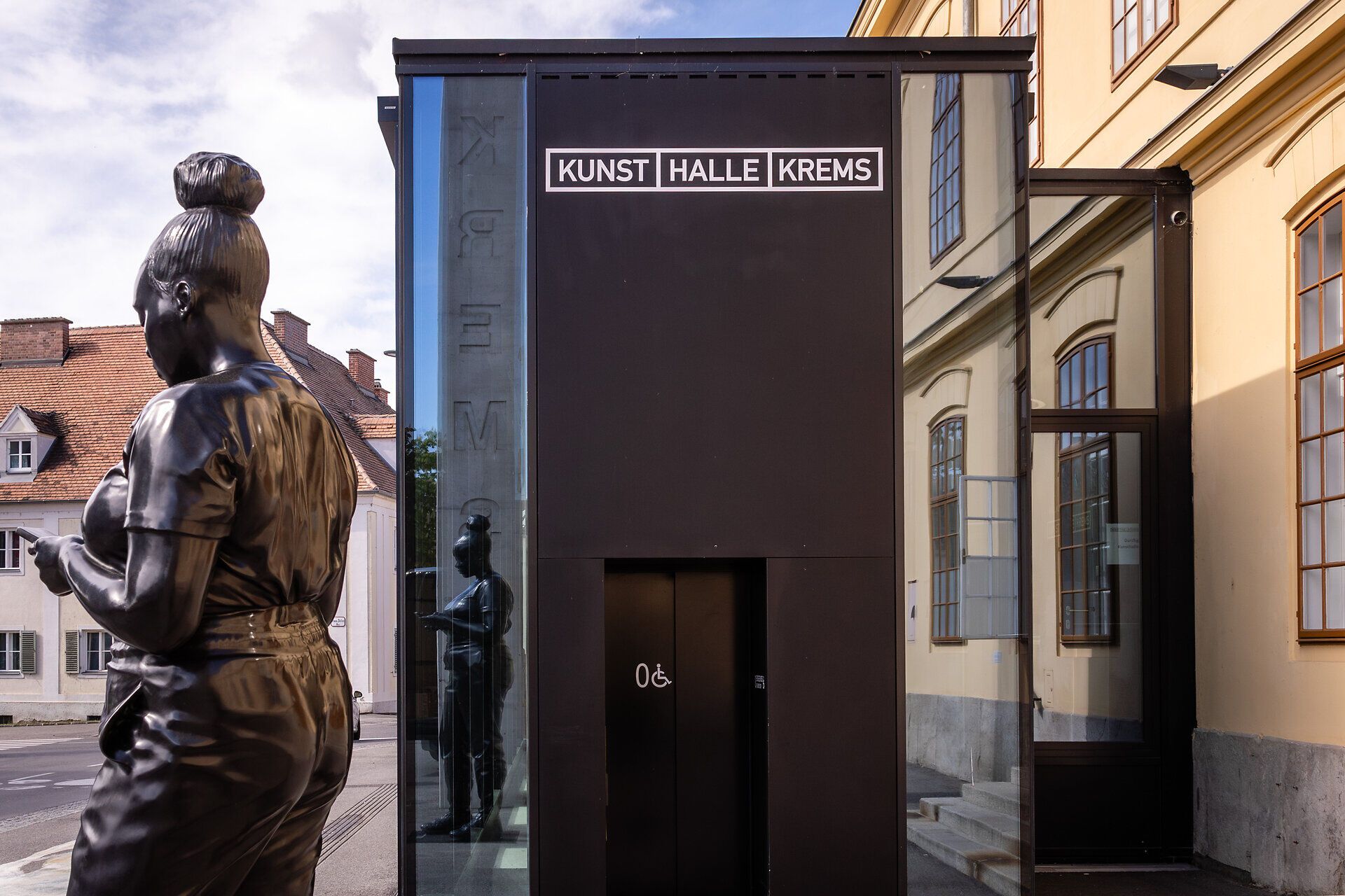 Eingang zur Kunsthalle Krems mit schwarzer Skulptur davor.