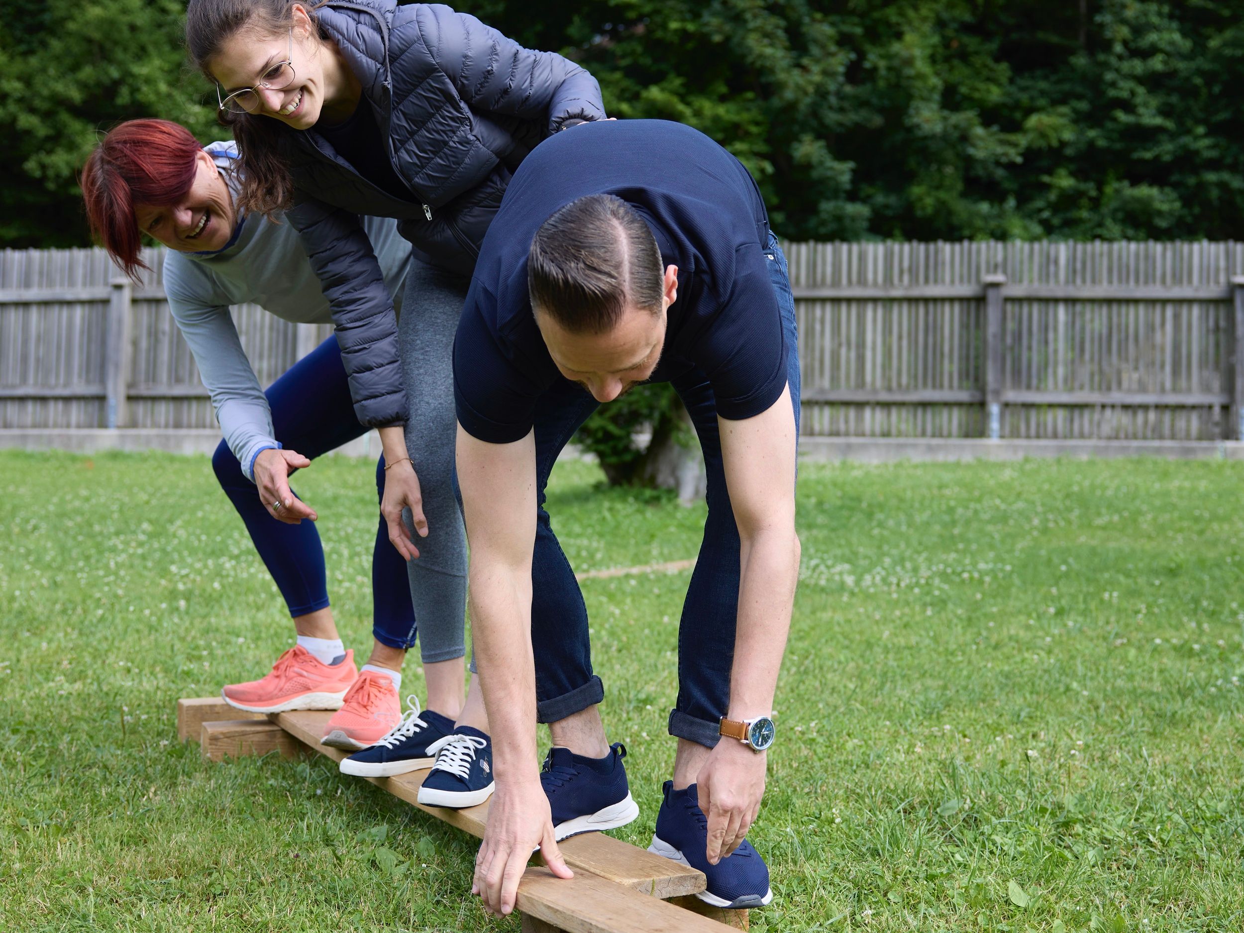 Teambuilding Spiel, eine Gruppe Menschen balanciert auf einem Brett