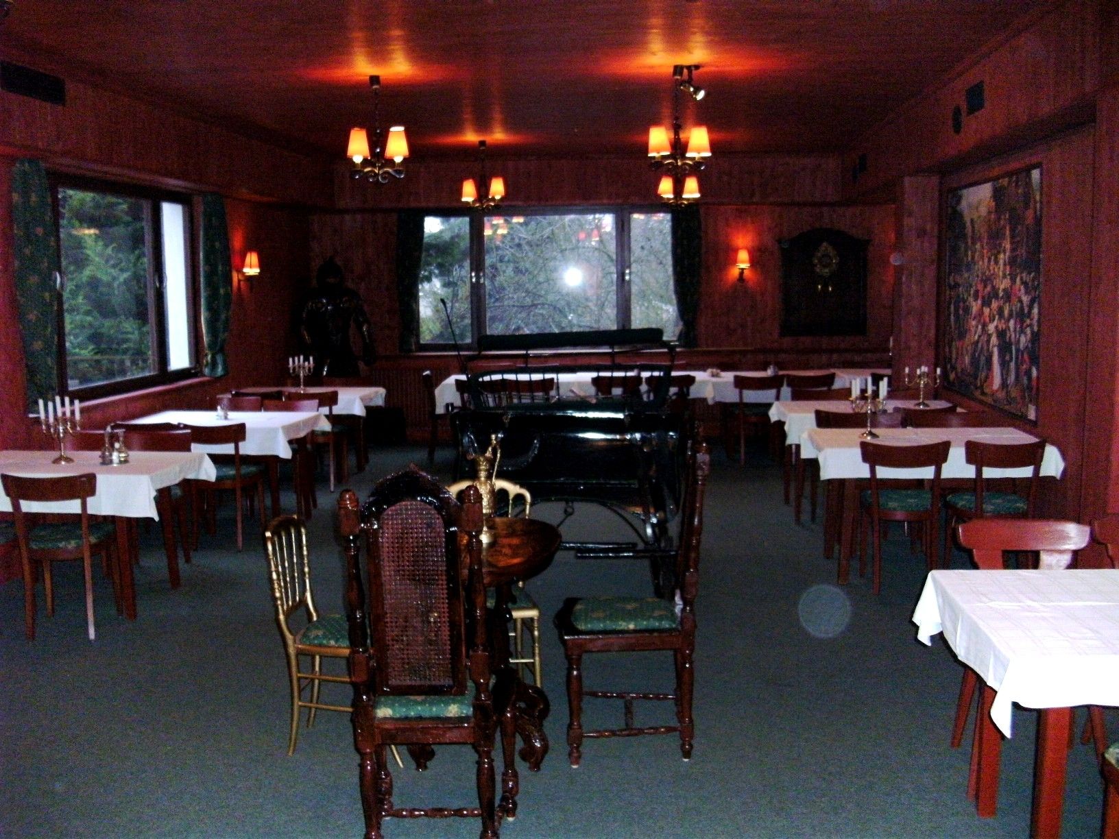 Ein rustikaler Festsaal mit Holzwänden, gedeckten Tischen und einem Klavier im Hintergrund.