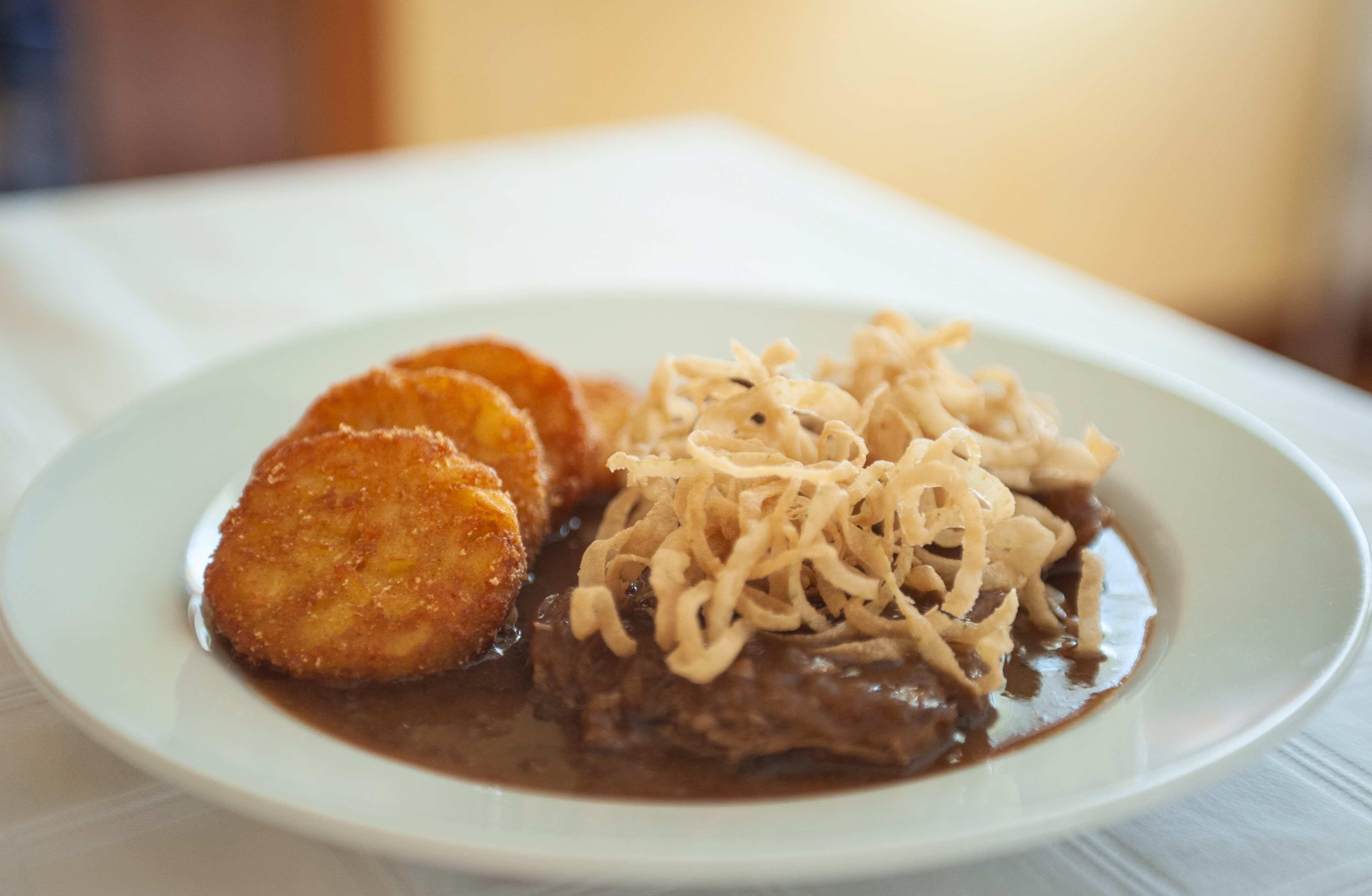 Ein Teller mit Röstis, Bratensoße und Röstzwiebeln.