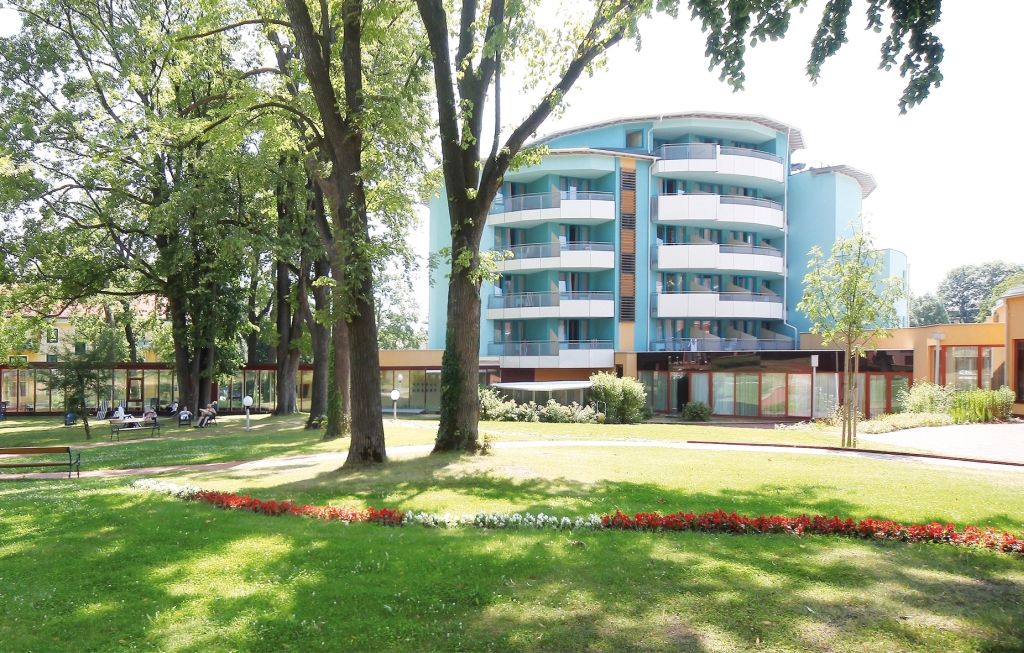 Modernes Gebäude mit Balkonen und Garten im Vordergrund.