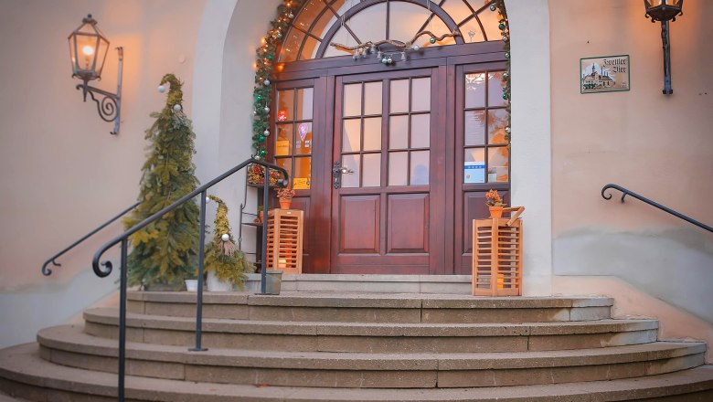 Eingang, © Schlossschenke Eingang mit dekorierten Weihnachtsbäumen und Lichtern.