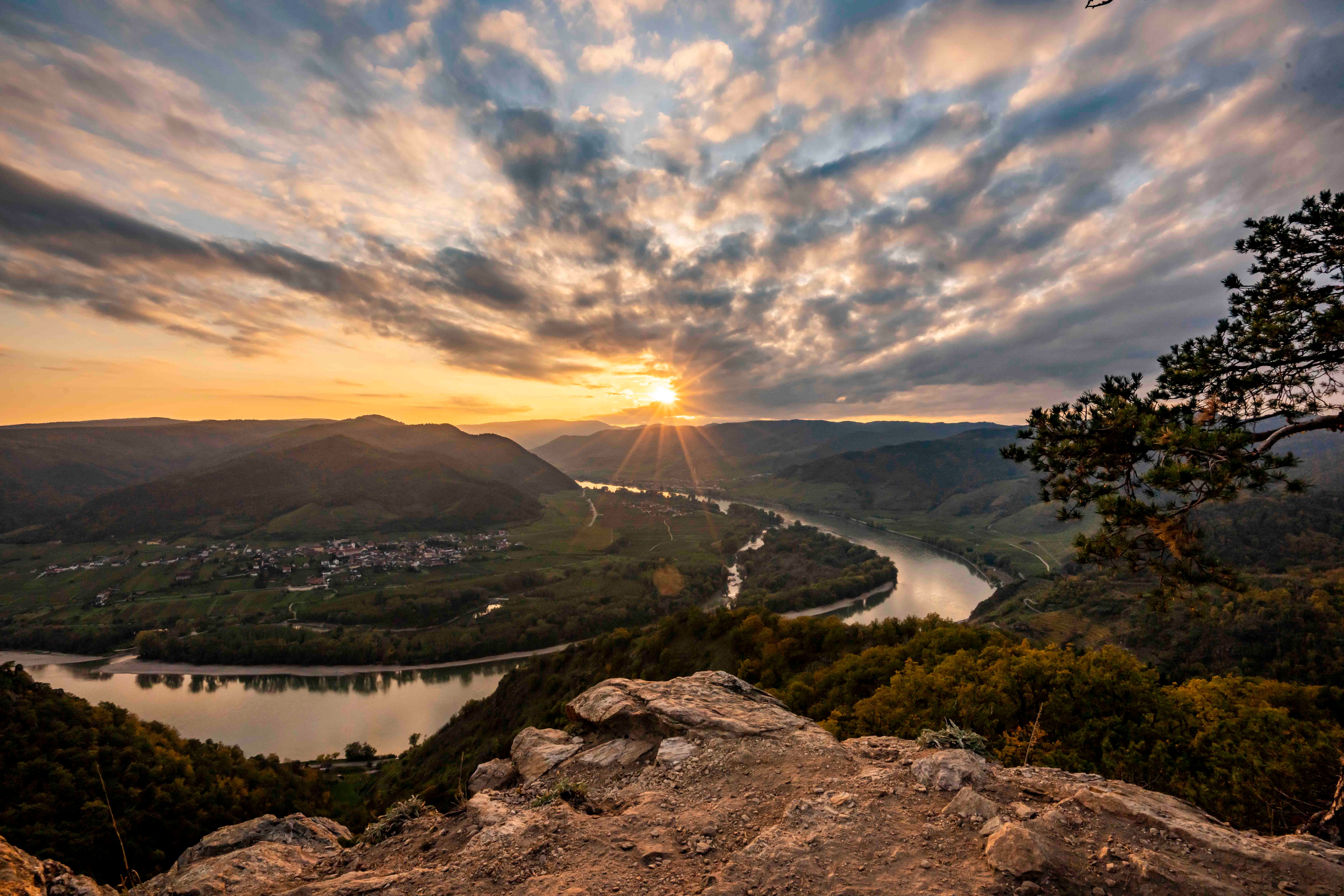 Sonnenuntergang über der Donau in Dürnstein, mit Blick auf Fluss und Hügel.