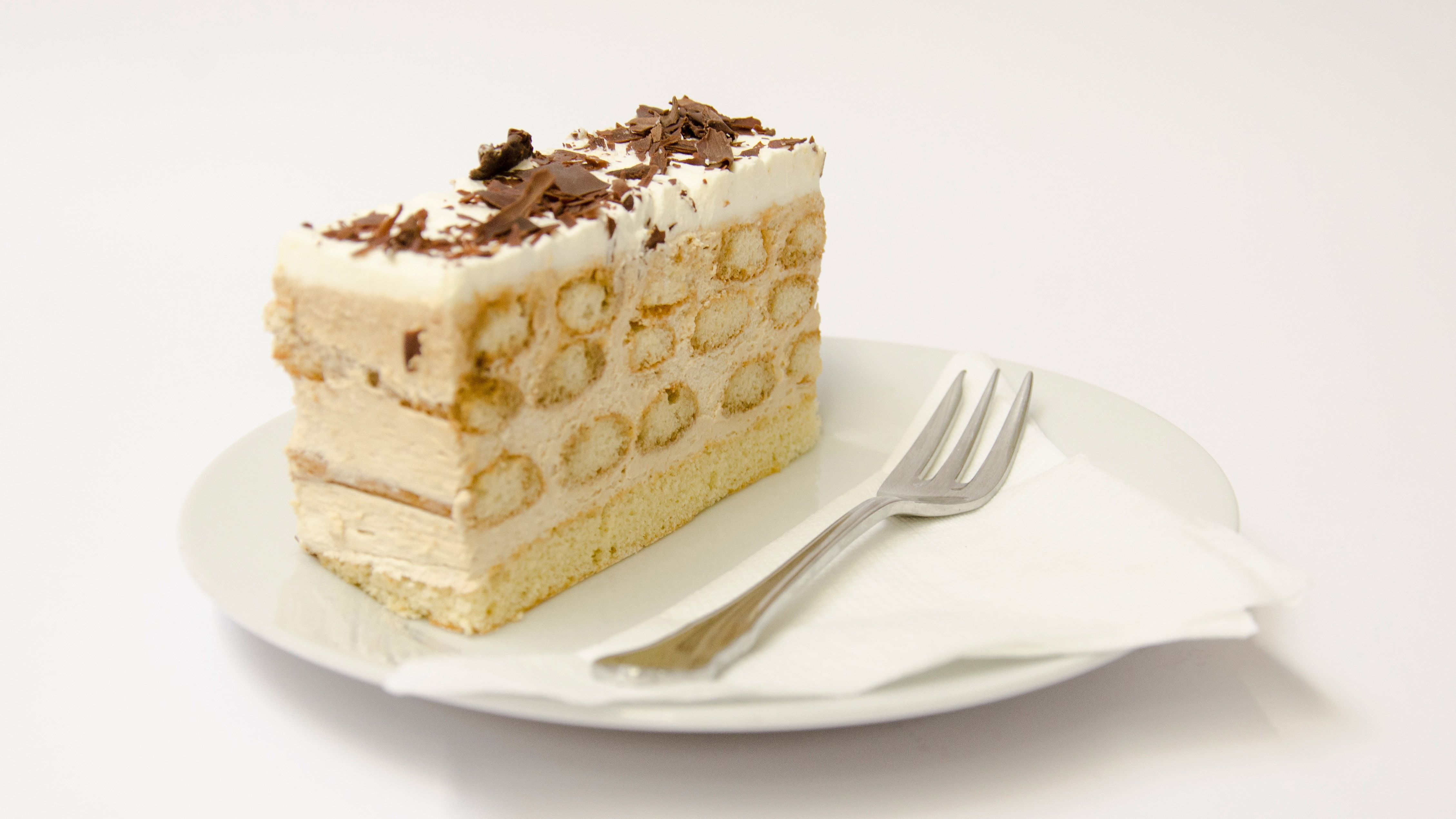 Ein Stück Malakofftorte auf einem Teller mit einer Gabel.