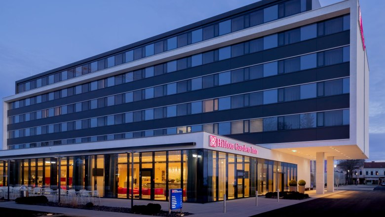 Hotelansicht, © Hilton Garden Inn Wiener Neustadt Außenansicht eines modernen Hotels bei Dämmerung.
