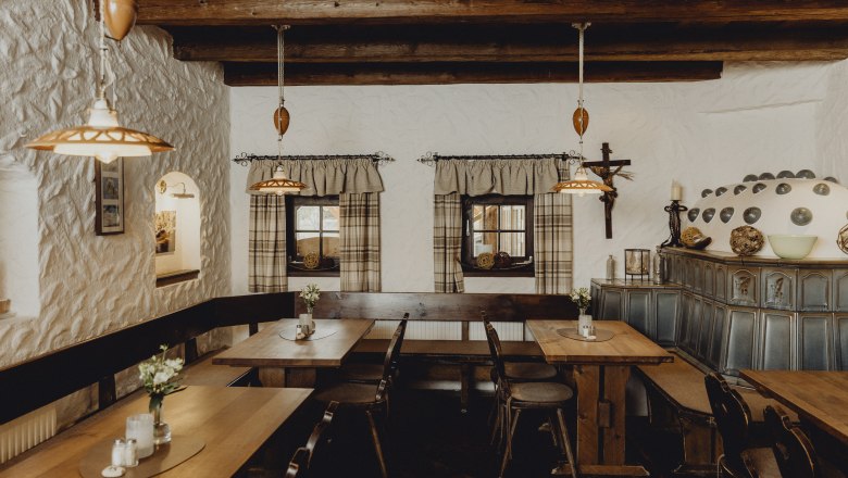 Gem&uuml;tliche Stube mit Holzm&ouml;beln, Kachelofen und rustikaler Dekoration.