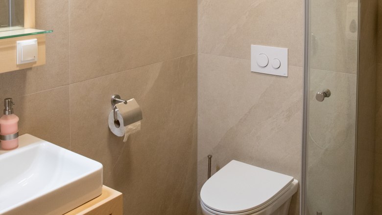 Modernes Badezimmer mit Waschbecken, Toilette und Duschkabine.