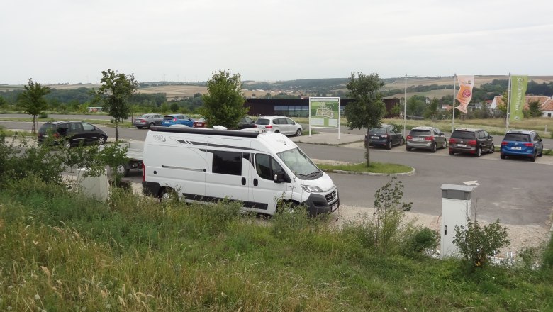 Wohnmobil auf einem Parkplatz mit umliegender Landschaft.