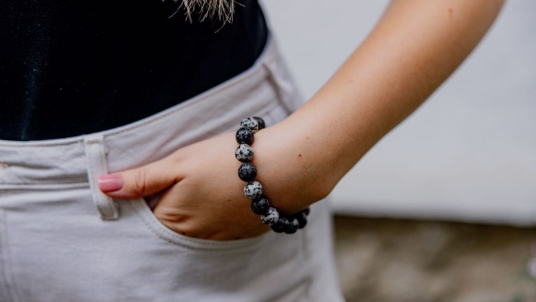 Nahaufnahme eines Armbands aus Granit an einem Handgelenk, Hand in Hosentasche.