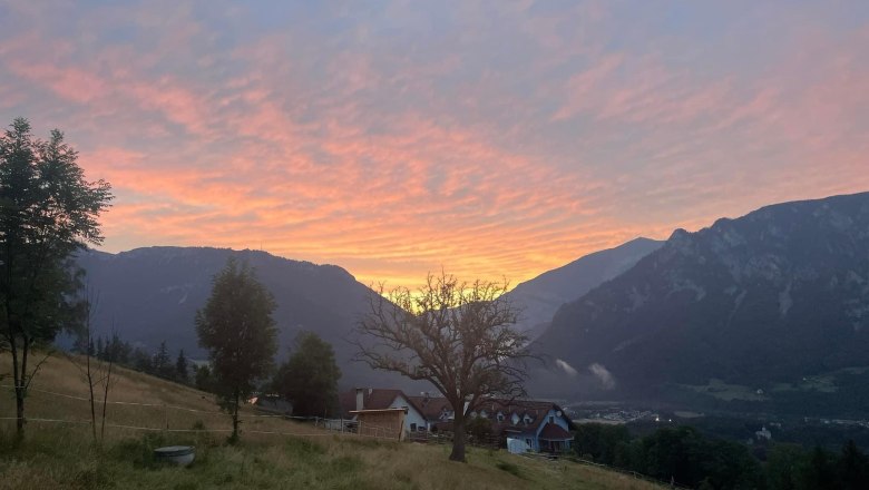 Blick auf ein Haus in einer Berglandschaft bei Sonnenuntergang.