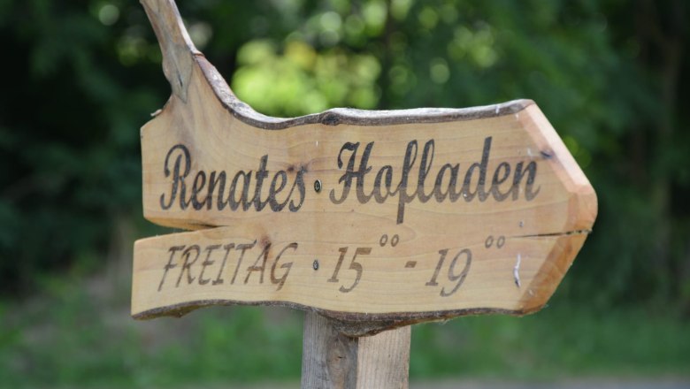Holzschild mit der Aufschrift 'Renates Hofladen' und &Ouml;ffnungszeiten 'Freitag 15-19 Uhr'.