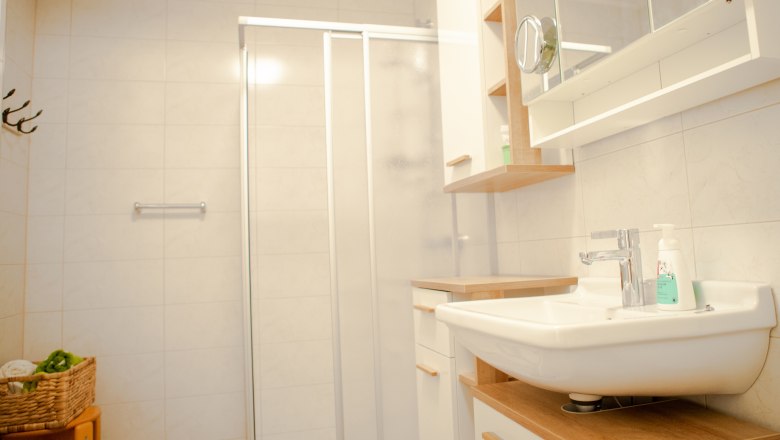 Modernes Badezimmer mit Dusche, Waschbecken und Spiegel.